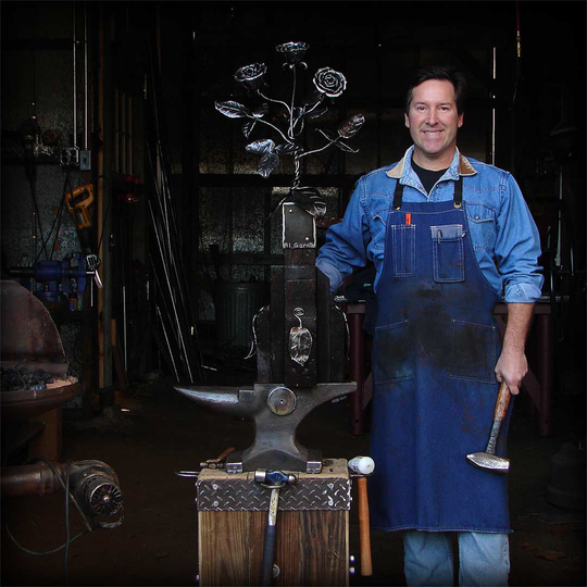 Blacksmith, Al Garnto, poses with hand forged roses out of steel in his sculpture shop, Blairsville, Ga.  